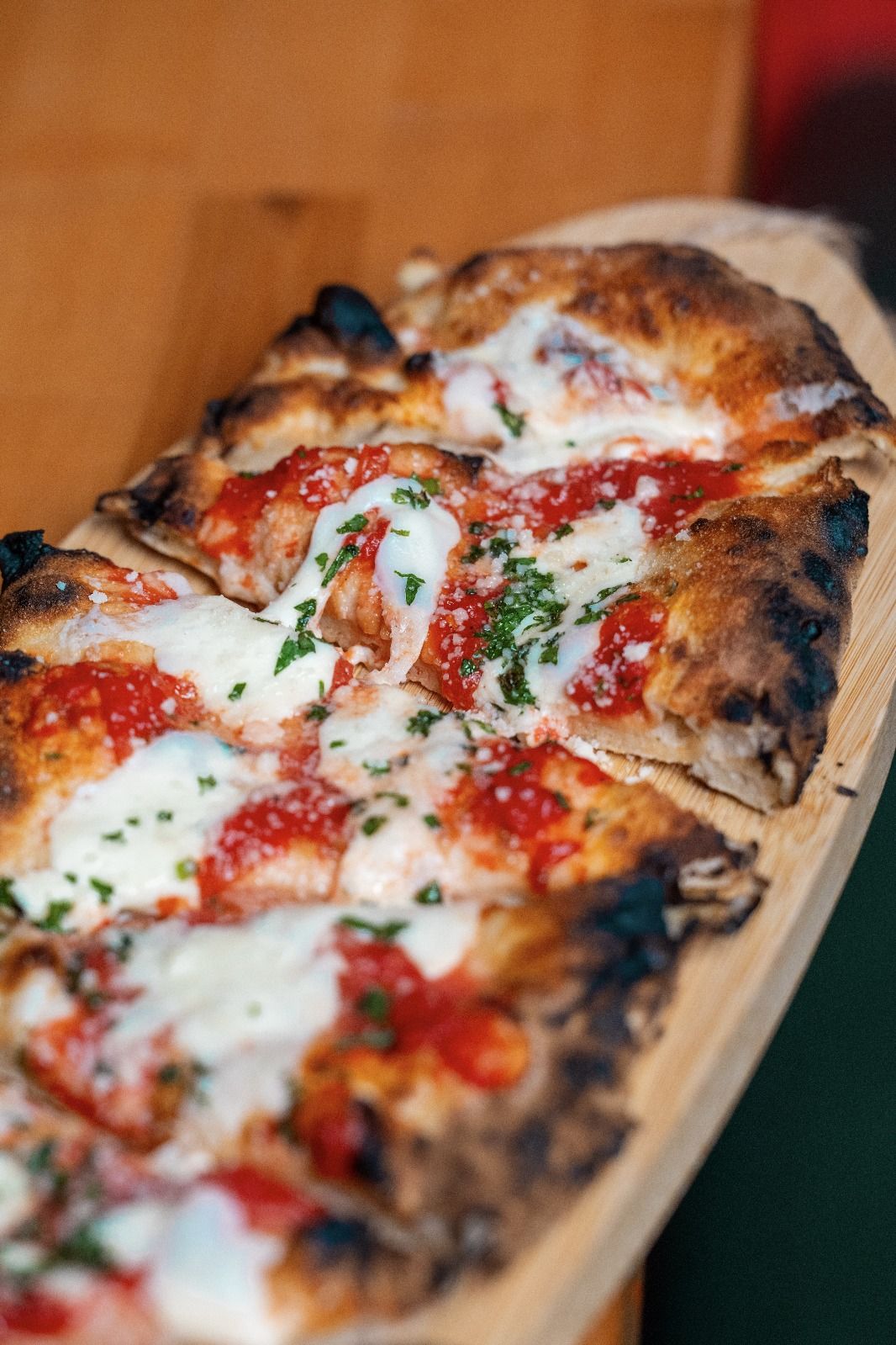 Roman-style pizza with tomato and mozzarella, sliced on a wooden board (opens Rosolini on Instagram)